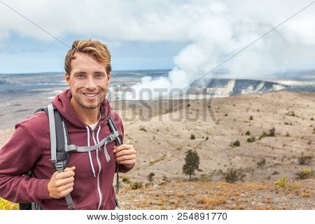 Hawaii volcano tourist man at Halemaumau crater in Kilauea caldera in Hawaii Volcanoes National Park, big Island with volcanic clouds and ash from eruption.
