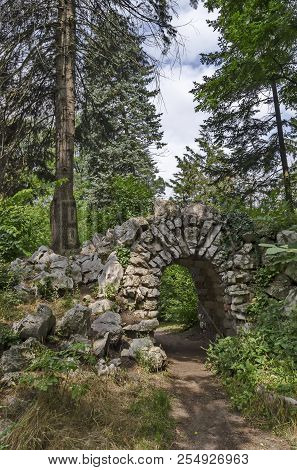 View Of Old Abandoned Rockery And Stone Arch Brushy With Various Plant In The  Natural Old West Park