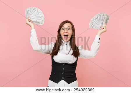 Young Surprised Business Woman In Glasses Holding Bundle Lots Of Dollars, Cash Money Spreading Hands