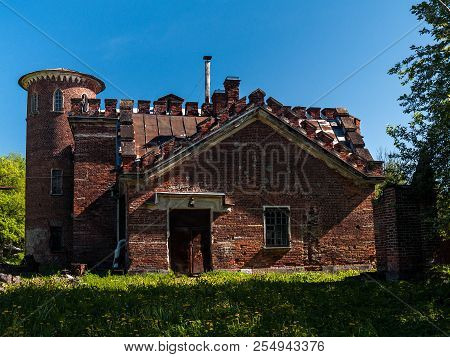 The Facade Of The Building Of The Old Stables Of Red Baked Brick With A Round Turret, Crenellated Ro