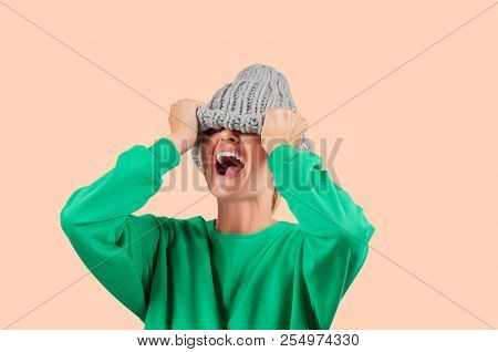 Furious. Emotional Angry Woman Is Pulling Wool Hat Over Her Eyes On Pastel Background