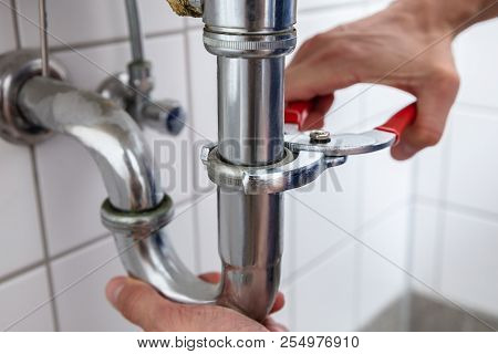Plumber Repairing Sink With Adjustable Wrench