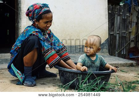 Luang Namta / Laos - Jul 06 2011: Lolo Tribal Woman Giving A Bath To Her Kid In A Bucket