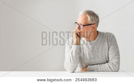 old age, problem and people concept - close up of senior man in glasses thinking