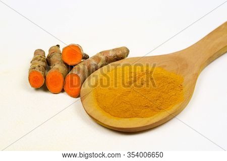 Turmeric Powder In A Wooden Spoon And Fresh Turmeric Roots Isolated On A White Background Is An Ingr