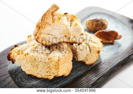 Burnt ciabatta with two kinds of butter. Aromatic fresh bread on wooden cutting board. Delicious rustic meal and cooking utensil. Traditional italian dish. Food presentation, pastry on white surface