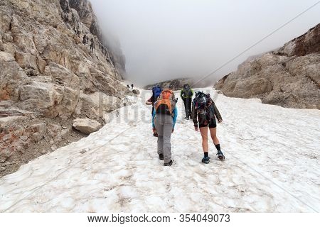 People Hiking Towards Col Bocca Del Tuckett On Snow Field In Brenta Dolomites Mountains, Italy