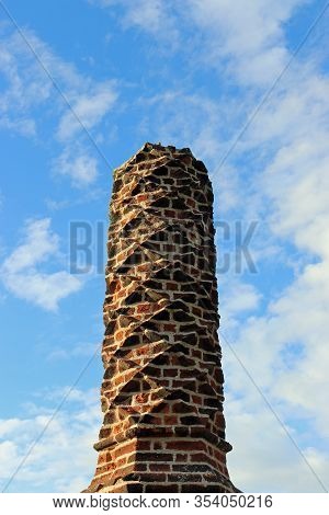 Tudor Barley Sugar Twist Red Brick Chimney Pot With A Blue Sky With White Cloud Background.