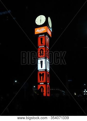 Laima Clock - Traditional Meeting Place In Riga - At Night, Brightly Illuminated In Red White Red Fo