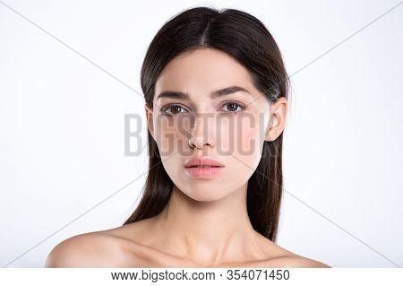 Portrait of beautiful young brunette woman with clean face. Beautiful face of young adult woman with clean fresh skin - isolated on white. Front portrait of woman with beauty face. Beauty concept 