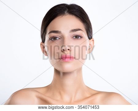 Portrait of beautiful young brunette woman with clean face. Beautiful face of young adult woman with clean fresh skin - isolated on white. Front portrait of woman with beauty face. Beauty concept 