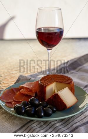 Tastes Of Spain, Jamon Iberian, Black Olives, Manchego Cheese With Red Paprika And Glass With Red Ri