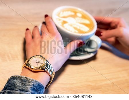 Hand Of Woman Holding Cup Of Cappucinno On Table