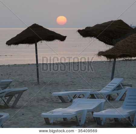 Solen stiger över en cafébar strand