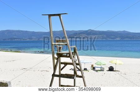 Beach With Wooden Lifeguard Chair, Beach Umbrellas And Turquoise Water With Blue Sky. Cee, Coruña, G