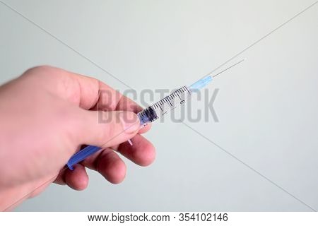 Injection Syringe In Hand On Light Background