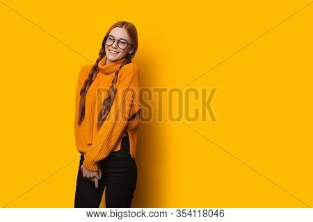 Charming Red Haired Caucasian Lady With Eyeglasses Is Smiling Happily And Posing Near Yellow Freespa