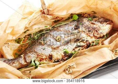 Baked dorado fish in parchment. Grilled tuna in black plate. Cooked dolphinfish with herbs. Served seafood restaurant food. Marine delicacy, mediterranean delicious gourmet meal