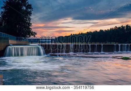 The Overflow At Penrith Weir As The Sunset Colours Some Of The Clouds In The Sky And Reflects In The