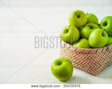 Apples Harvest Concept. Braided Bamboo Basket With Green Apples On White Wooden Background With Copy