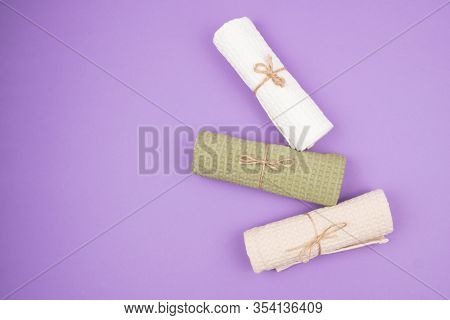 Three-folded Into A Roll And Tied With A Rope Towels On A Purple Background. The View From The Top.