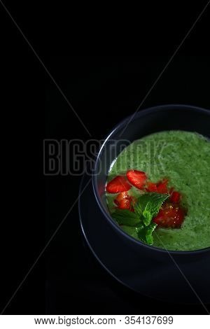 Green Spinach Soup Decorated With Strawberries And Mint On A Black Background. Copy Space. A Concept