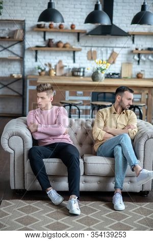 Two Men Sitting On The Sofa Not Loooking At Each Other