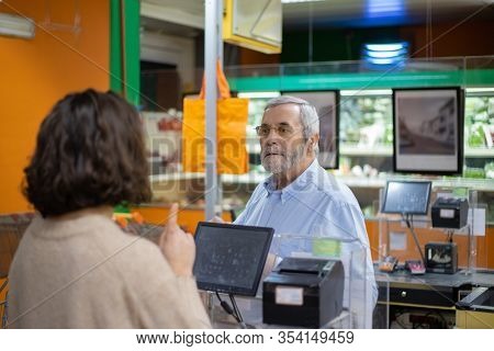 Man And Woman Talking At Pay Desk In Supermarket. Customer Talking With Cahier While Buying Goods In