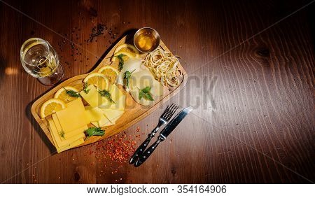 Assorted Different Types Of Cheese On A Wooden Board.top View