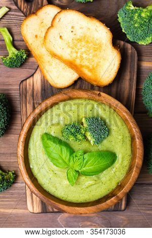 Ready To Eat Fresh Hot Broccoli Puree Soup With Slices Of Broccoli And Basil Leaves In A Wooden Plat