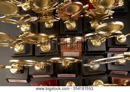 Group of golden trophy over blackboard background. top view. flat lay.Trophy is a specific achievement, serves as recognition / evidence of merit, awarded for sporting events