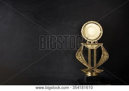 Golden trophy over blackboard background. top view. flat lay.Trophy is a specific achievement, serves as recognition / evidence of merit, awarded for sporting events