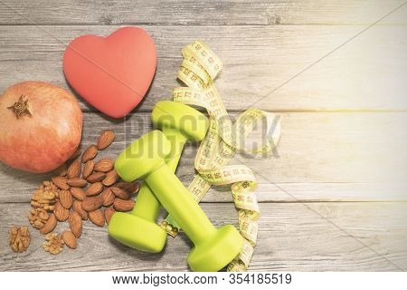 Pomegranate Fruit, Dumbbells, Measuring Tape On The Background Of A Wooden Texture. Fitness, Sports 