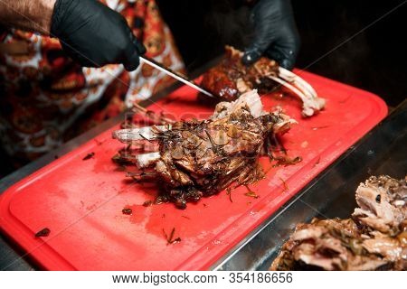 Chev Cuts Juicy Cooked Meat, Separating The Meat From The Bone With A Knife.