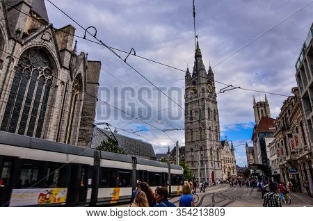 Ghent, Belgium, August 2019. The Bell Tower Called Beffroi Behind The Church Of St. Nicholas.