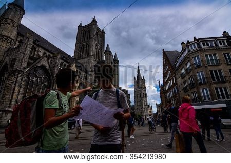 Ghent, Belgium, August 2019. Two Boys Consult The Tourist Map, Behind Them We Recognize The Church O
