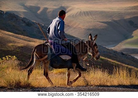 Dushanbe, Tajikistan. August 06, 2019. A Peasant On A Donkey Rides Along The Pamir Highway On His Ow