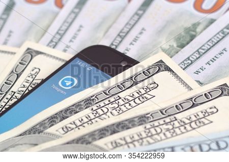 Smartphone Screen With Telegram App And Lot Of Hundred Dollar Bills. Business And Social Networking 