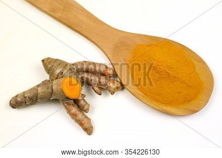Turmeric Powder In A Wooden Spoon And Fresh Turmeric Roots Isolated On A White Background Is An Ingr