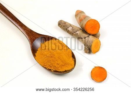 Turmeric Powder In A Wooden Spoon And Fresh Turmeric Roots Isolated On A White Background Is An Ingr