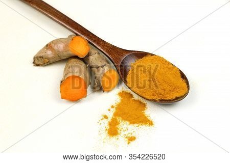 Turmeric Powder In A Wooden Spoon And Fresh Turmeric Roots Isolated On A White Background Is An Ingr