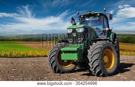 Russia, Krasnodar region, Kushevsky district.16.10.2018.   Modern, green tractor in the spring field work on the background of a beautiful rural landscape.