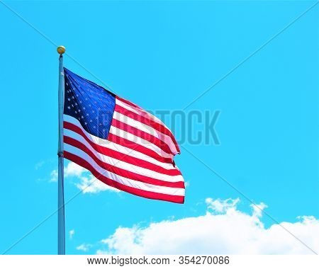 American Flag Pole With Flag Against A Blue Sky