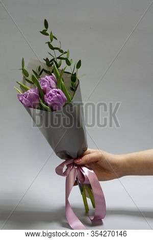 Female Hands Holding A Minimalistic Spring Bouquet Of Purple Tulips And Ruskus, Selective Focus
