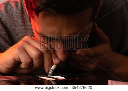Close Up Photo Of The Young Man Sniffing A Line Of Cocain With Dollar Banknote