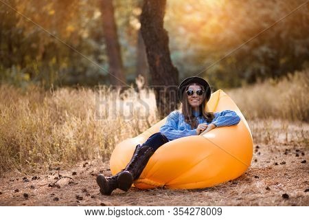 Autumn Lifestyle Portrait Of Pretty Girl In Stylish Sunglasses And Black Hat Sitting On Orange Infla