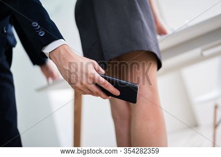 Man Taking Upskirt Photo Of Woman In Office