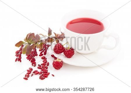 Healthy fruit tea with barberries and raspberries in white cup and branch of berberry isolated on white background.