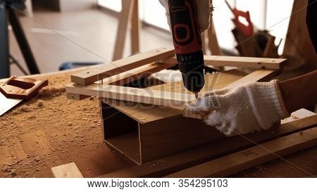 Carpenter Using Drill To Screwing Pieces Of Board At Site.