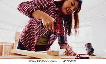 Female Carpenter Using Drill To Screwing Pieces Of Board At Site.